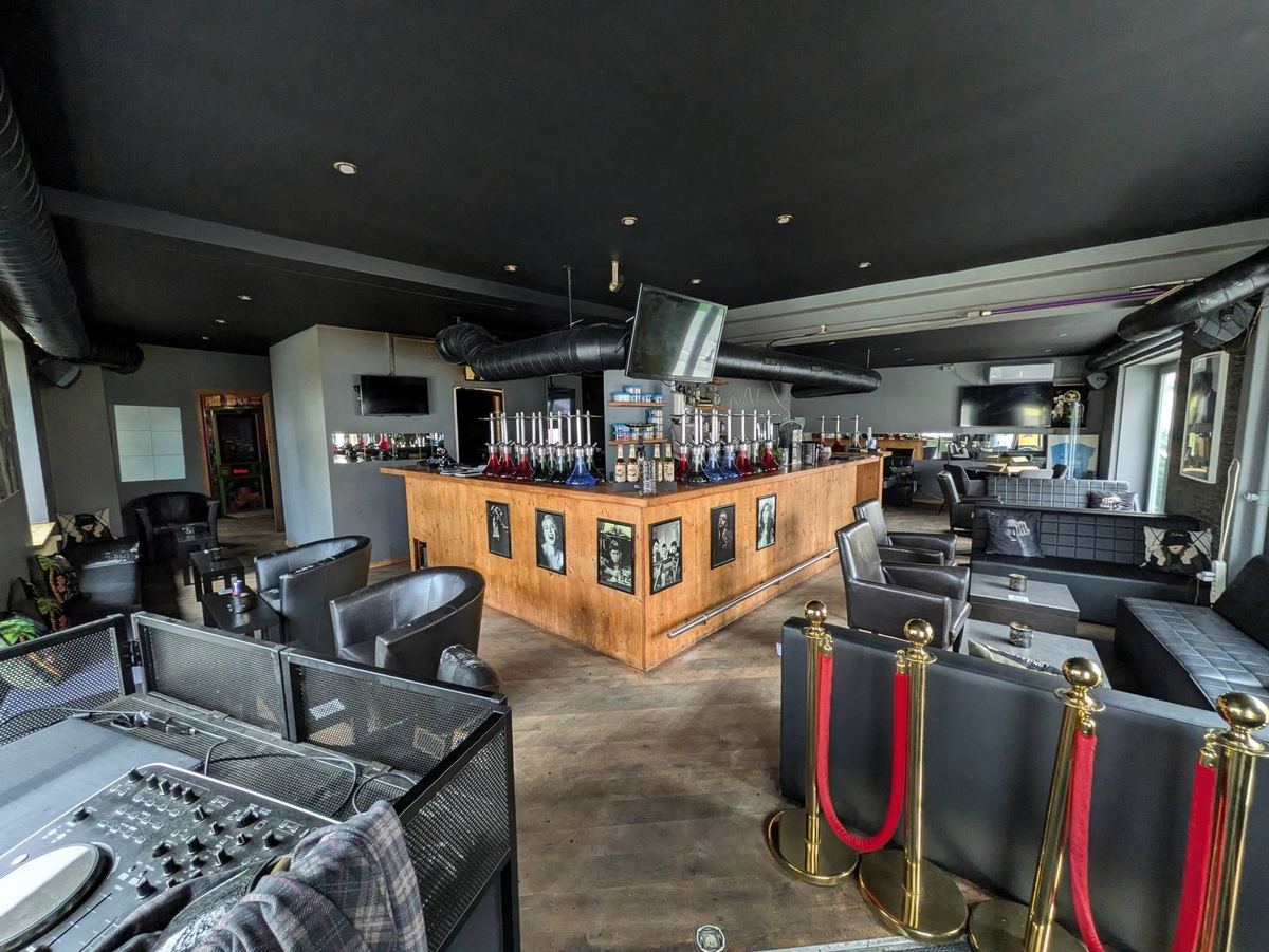 Blick in die Show Lounge: Holzbar mit Shishas, Ledersessel und DJ-Pult